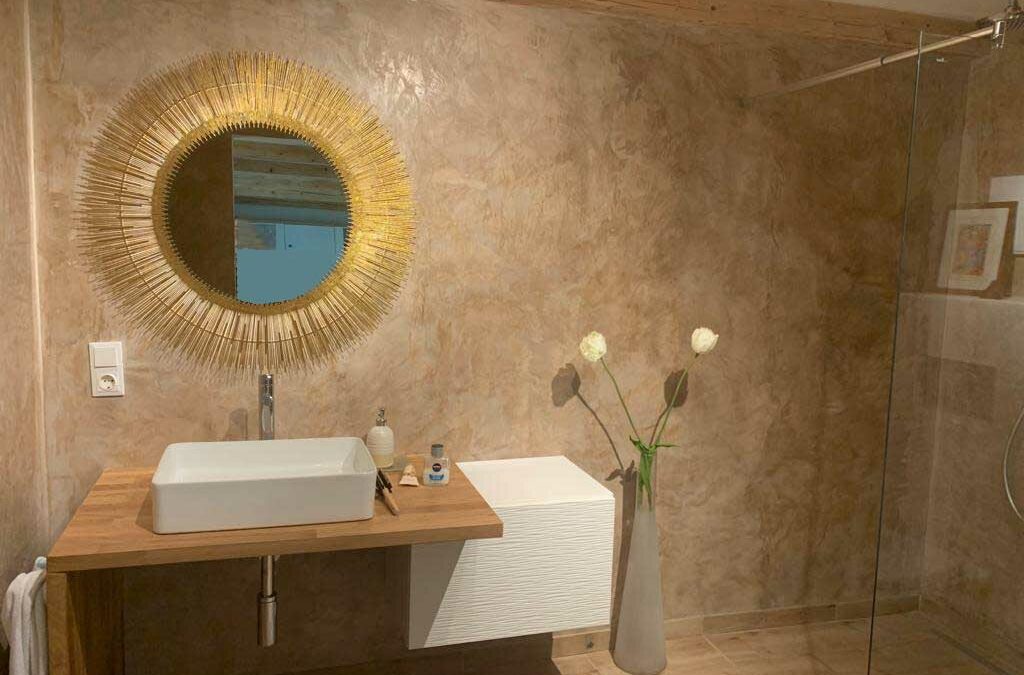 Erdfarbener Marmorputz im Badezimmer mit rundem Spiegel an der Wand