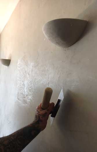 Worker smoothing marble plaster