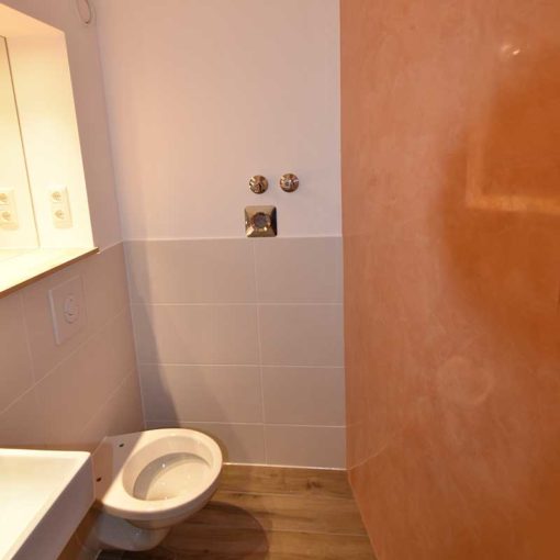 Stuc vénitien un mur rouge-orange dans les toilettes